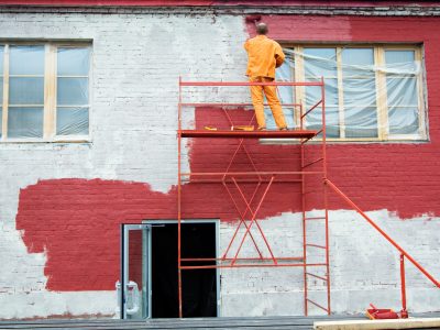Man painting a brick wall in red